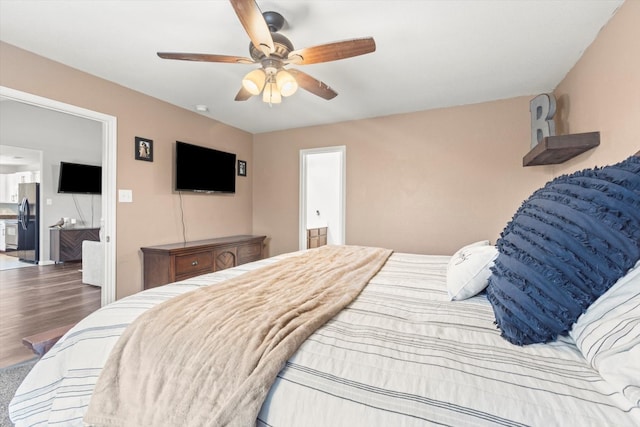 bedroom featuring black refrigerator, ensuite bathroom, ceiling fan, and hardwood / wood-style floors