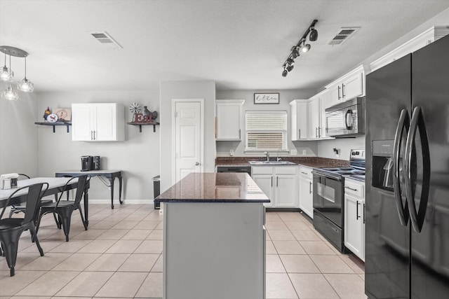 kitchen with black appliances, white cabinets, hanging light fixtures, light tile patterned floors, and a kitchen island