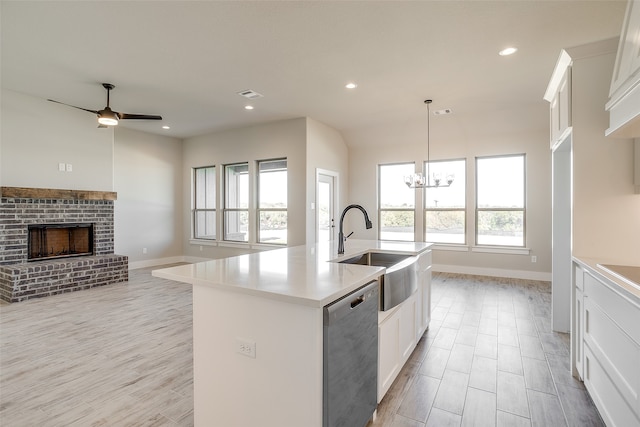 kitchen featuring dishwasher, white cabinets, hanging light fixtures, and a center island with sink