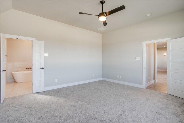 unfurnished bedroom with ceiling fan, vaulted ceiling, light carpet, and ensuite bath