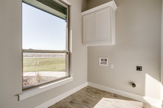 washroom with cabinets, hookup for a washing machine, light hardwood / wood-style floors, and electric dryer hookup