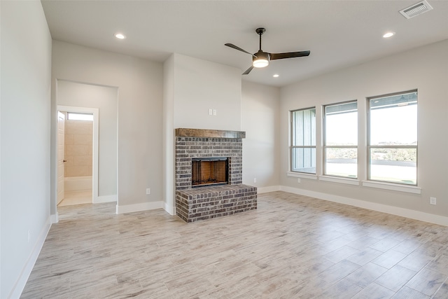 unfurnished living room featuring ceiling fan, light hardwood / wood-style floors, and a brick fireplace