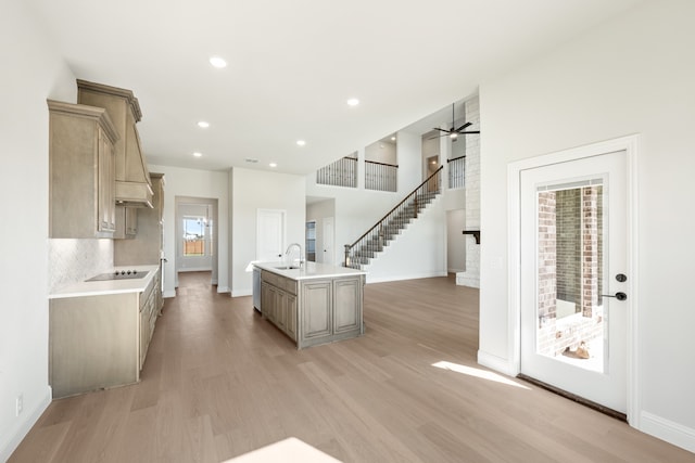 kitchen with ceiling fan, light brown cabinets, light hardwood / wood-style floors, a kitchen island with sink, and black electric stovetop