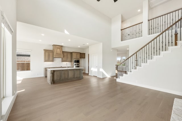 unfurnished living room featuring a high ceiling, light hardwood / wood-style flooring, and plenty of natural light