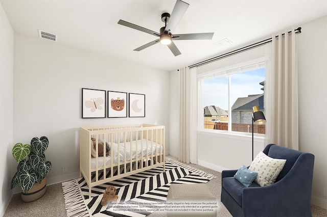 bedroom featuring carpet, ceiling fan, and a crib