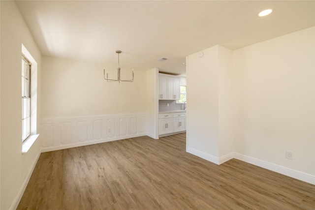 spare room featuring an inviting chandelier and light hardwood / wood-style flooring