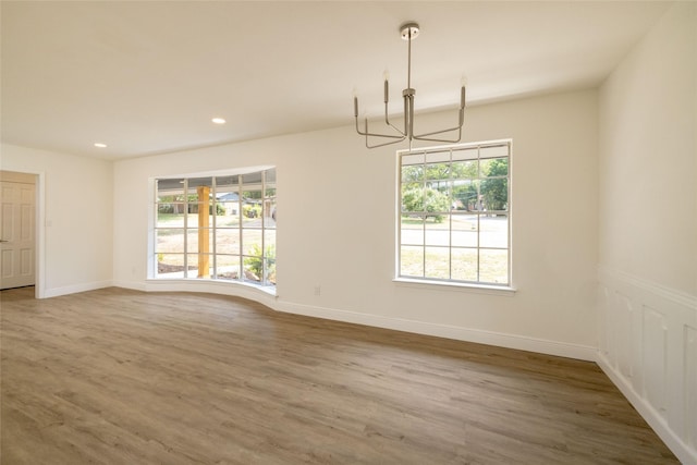 unfurnished dining area with hardwood / wood-style flooring, plenty of natural light, and a chandelier