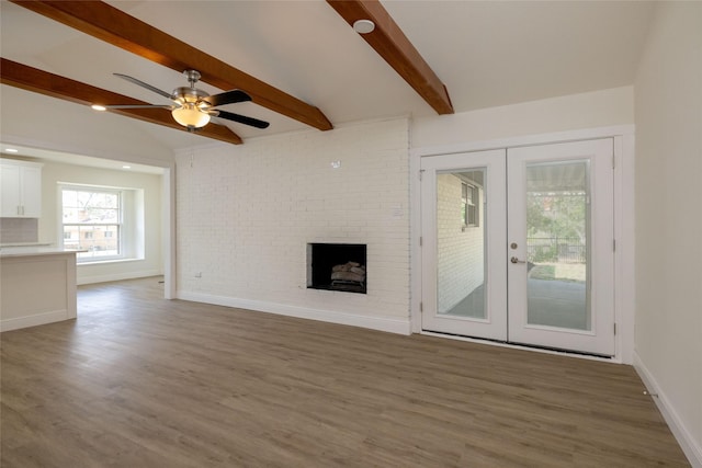 unfurnished living room with a brick fireplace, dark hardwood / wood-style floors, lofted ceiling with beams, and french doors