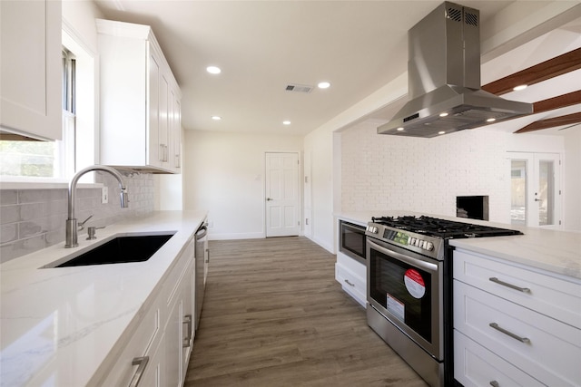 kitchen with sink, stainless steel appliances, island range hood, light stone countertops, and white cabinets