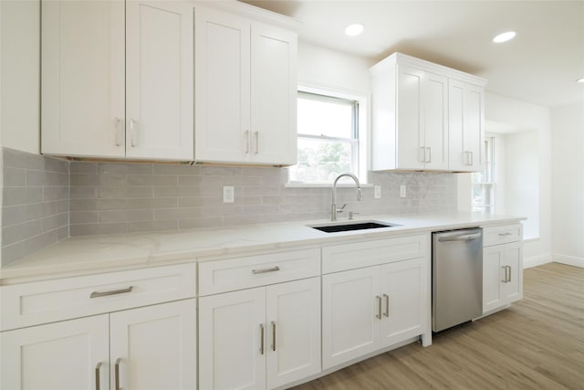 kitchen with sink, light hardwood / wood-style flooring, dishwasher, white cabinets, and backsplash