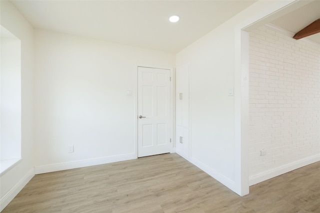 spare room featuring light hardwood / wood-style flooring and brick wall