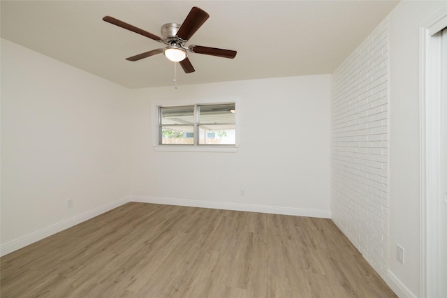 spare room with ceiling fan, brick wall, and light hardwood / wood-style flooring