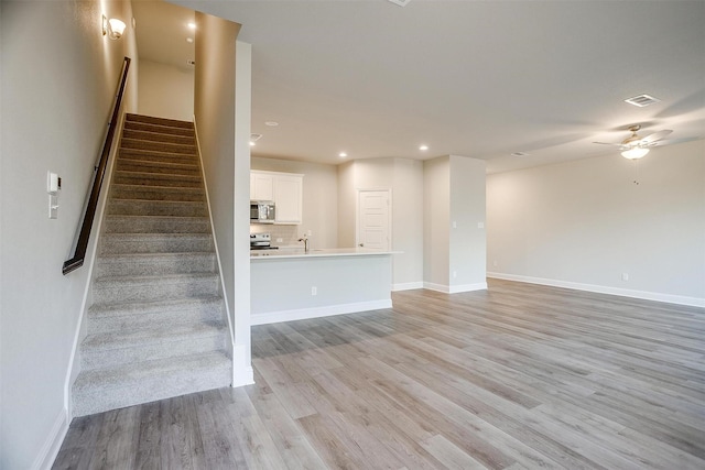 stairway with hardwood / wood-style flooring, ceiling fan, and sink