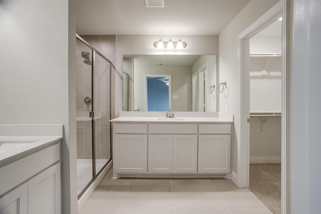 bathroom with an enclosed shower, vanity, and tile patterned flooring