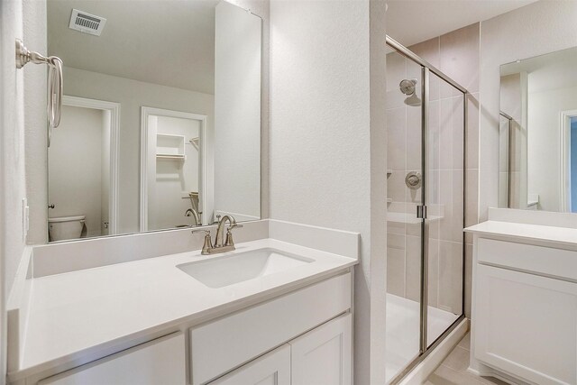 bathroom featuring vanity, an enclosed shower, and toilet