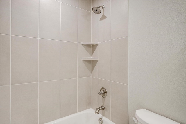 bathroom with toilet and tiled shower / bath combo