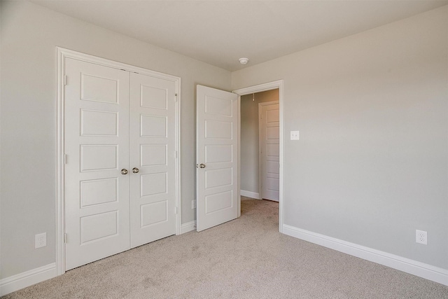 unfurnished bedroom featuring a closet and light carpet