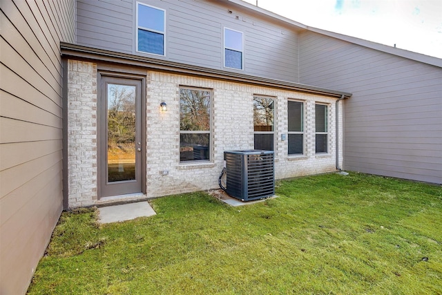 back of house featuring a lawn and central air condition unit