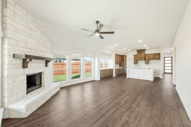 unfurnished living room with a fireplace, ceiling fan, dark wood-type flooring, and vaulted ceiling