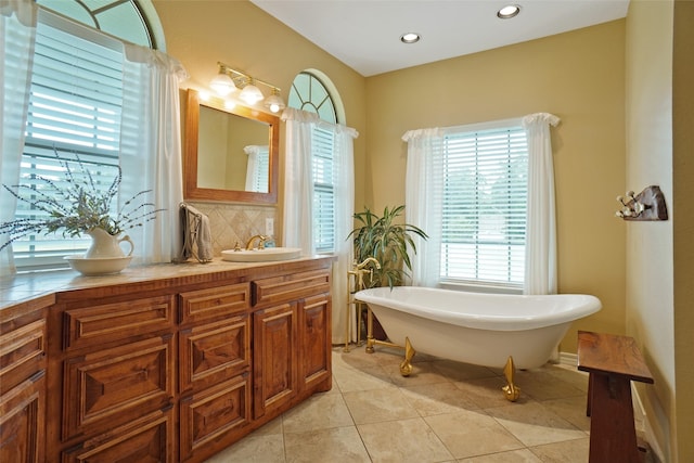 bathroom featuring vanity, tile patterned flooring, a bathing tub, and backsplash