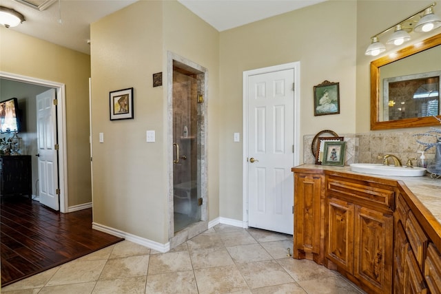 bathroom with tile patterned flooring, a shower with shower door, tasteful backsplash, and vanity