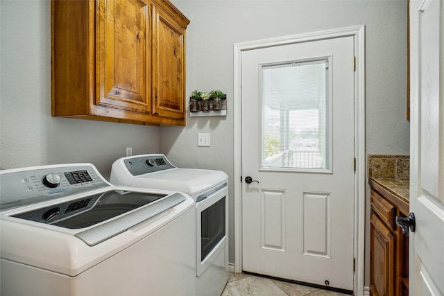 washroom featuring cabinets, washing machine and clothes dryer, and light tile patterned floors