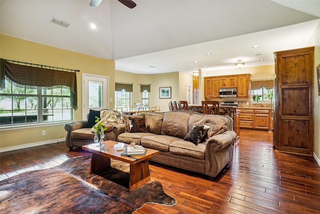 living room with a high ceiling, dark hardwood / wood-style flooring, and ceiling fan