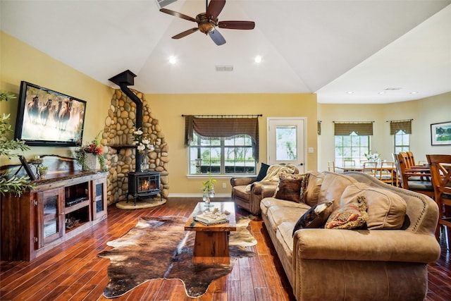 living room featuring a wood stove, a healthy amount of sunlight, vaulted ceiling, and dark wood-type flooring