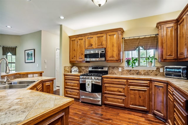 kitchen with dark hardwood / wood-style floors, stainless steel appliances, backsplash, and sink