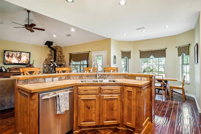 kitchen featuring lofted ceiling, ceiling fan, an island with sink, stainless steel dishwasher, and sink