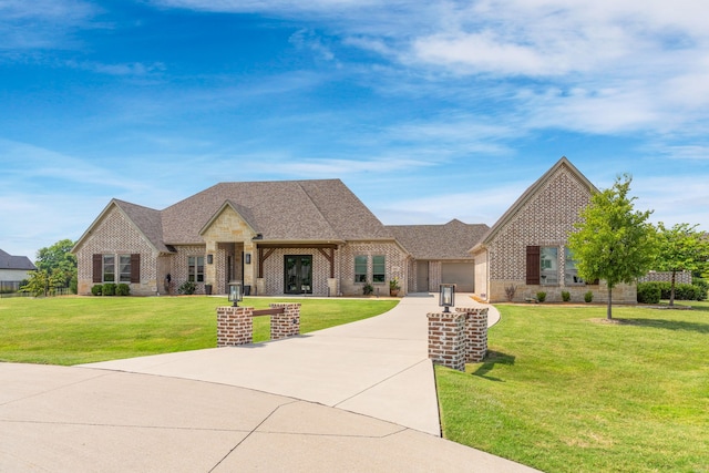 french country inspired facade featuring a garage, driveway, brick siding, and a front lawn