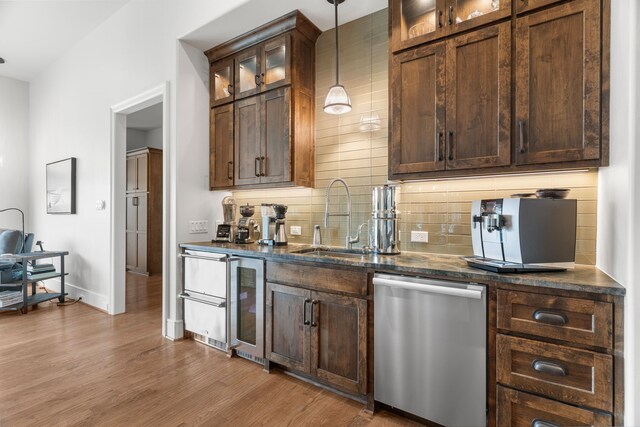 kitchen with decorative light fixtures, dishwasher, sink, decorative backsplash, and light wood-type flooring