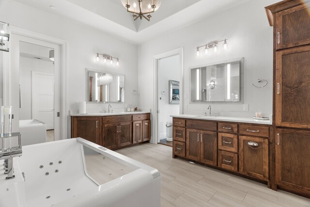 bathroom featuring hardwood / wood-style floors, a tub to relax in, a raised ceiling, and vanity