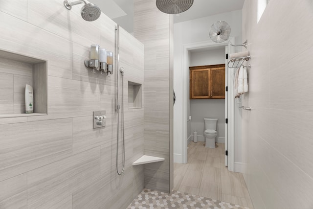 bathroom with tile patterned flooring, toilet, and a tile shower