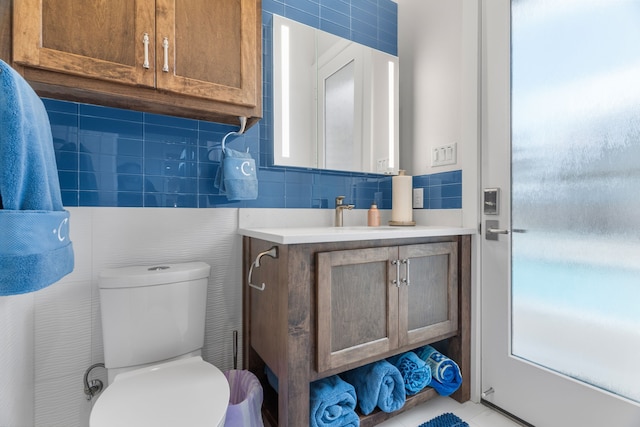 bathroom with tile walls, toilet, plenty of natural light, and vanity