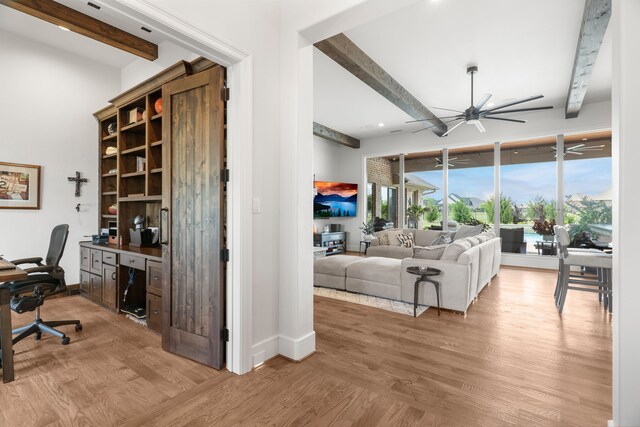 interior space featuring light wood-type flooring, ceiling fan, and beamed ceiling