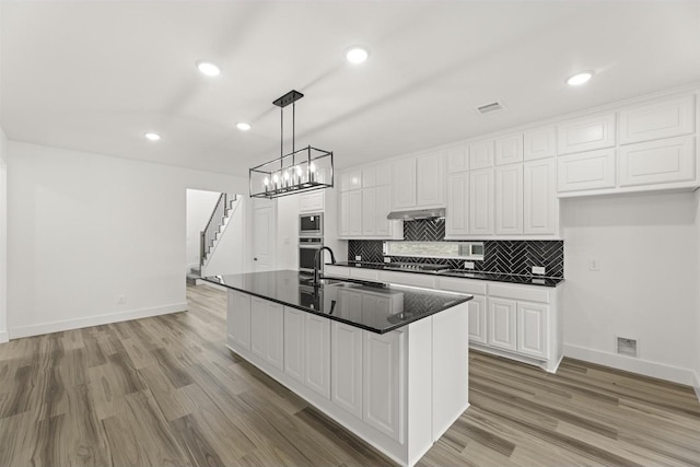 3104 Summer Rain Ln, Anna, TX 75409 - kitchen with dark countertops, under cabinet range hood, white cabinetry, appliances with stainless steel finishes, and recessed lighting