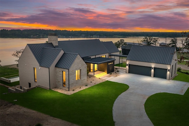 modern inspired farmhouse featuring a garage, a lawn, and a water view