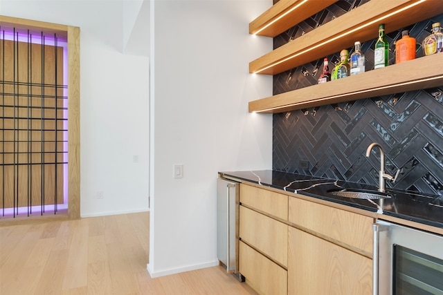 bar with sink, wine cooler, tasteful backsplash, light brown cabinetry, and light wood-type flooring