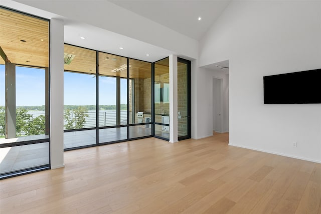 empty room with expansive windows, a high ceiling, and light wood-type flooring