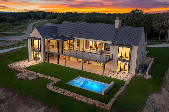 back house at dusk featuring a patio, central AC, and a yard