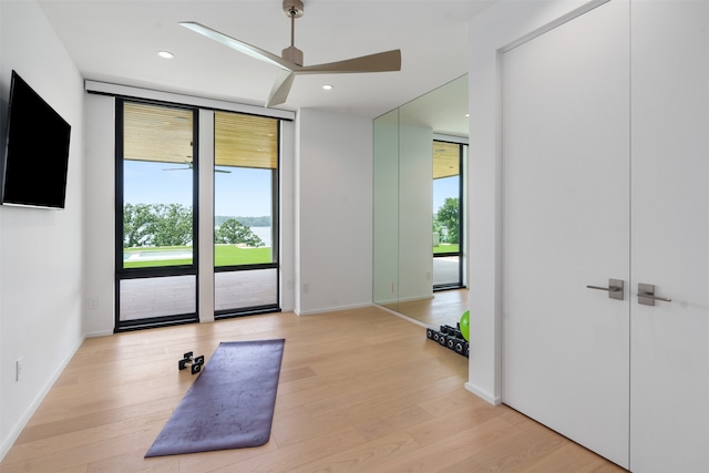 interior space with ceiling fan, a wall of windows, a healthy amount of sunlight, and light hardwood / wood-style floors