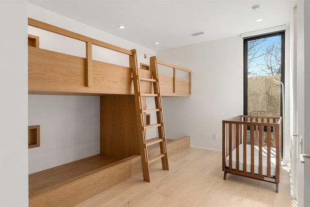 bedroom featuring a nursery area and light hardwood / wood-style floors