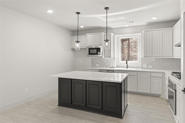 kitchen with white cabinetry, appliances with stainless steel finishes, a center island, and hanging light fixtures