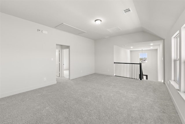 empty room with a healthy amount of sunlight, carpet flooring, and vaulted ceiling