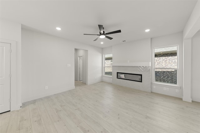 unfurnished living room featuring ceiling fan, light wood-type flooring, and a high end fireplace