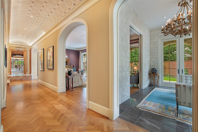 corridor with french doors, a notable chandelier, parquet floors, and crown molding