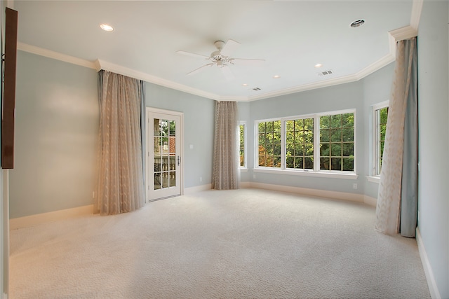 carpeted spare room featuring ceiling fan, crown molding, and a healthy amount of sunlight