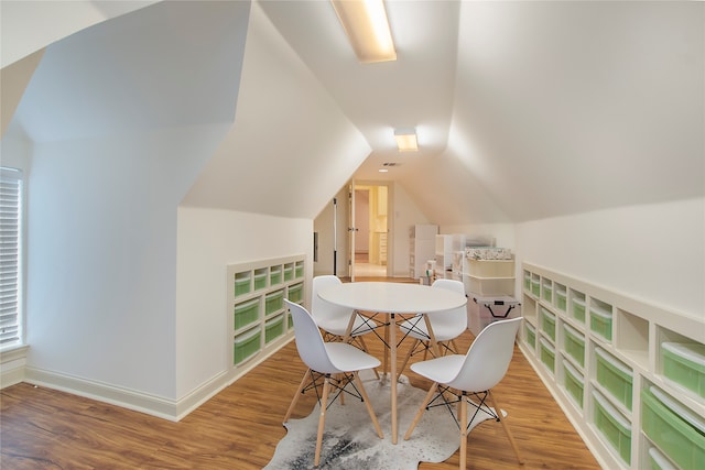 dining space featuring wood-type flooring, built in shelves, and lofted ceiling