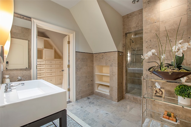 bathroom featuring a shower with shower door, tile walls, vaulted ceiling, and sink